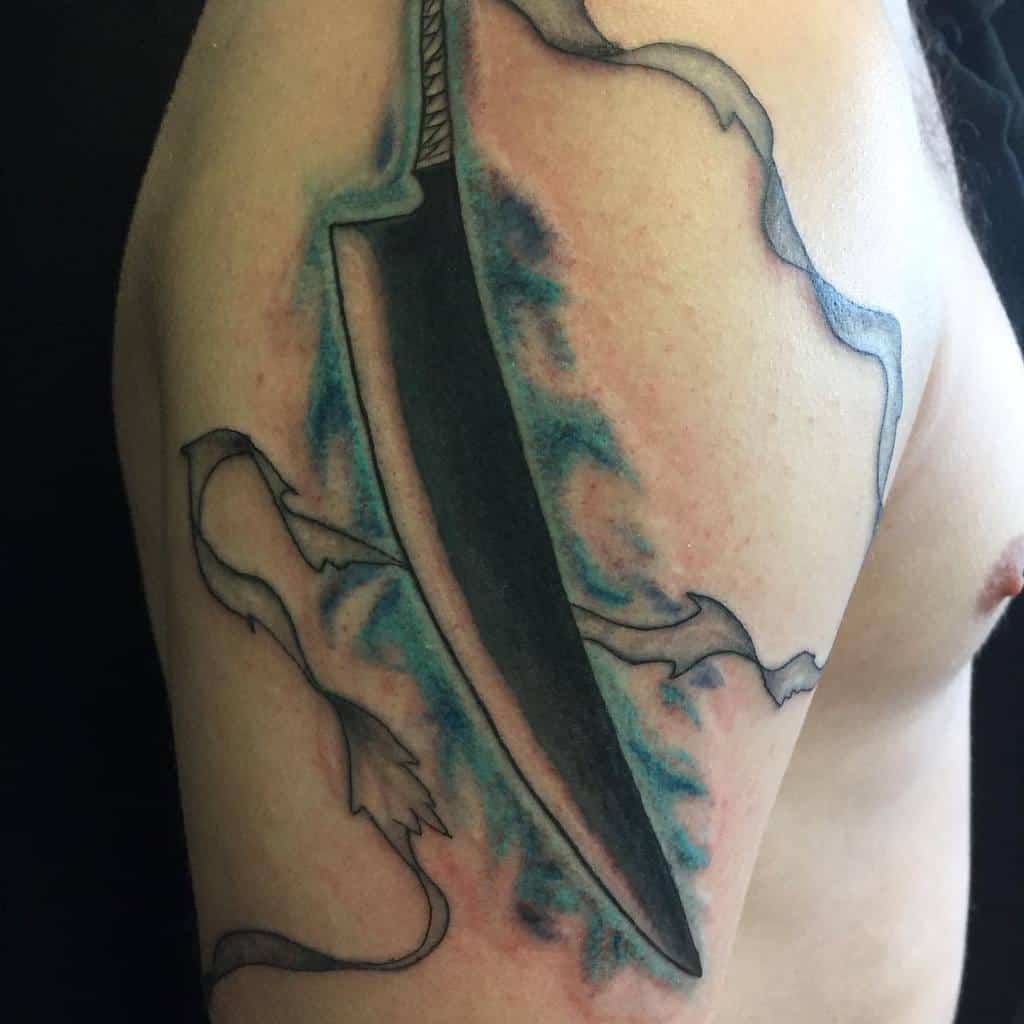 Colorful tattoo of Ichigo Kurosaki’s Zanpakutō from Bleach, featuring a bold black blade, flowing cloth details, and blue spiritual energy effects 