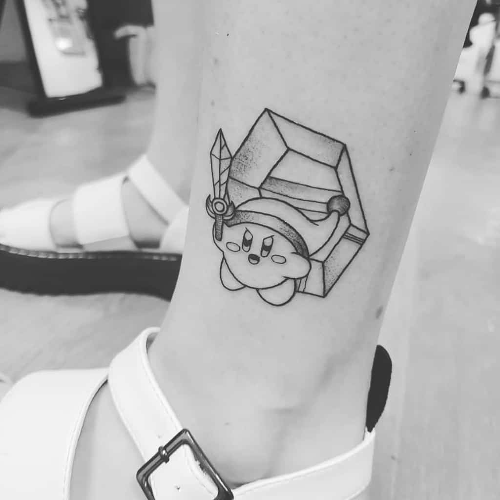 Black and white tattoo of Kirby dressed as Link from The Legend of Zelda, wielding a sword and floating in front of a large rupee