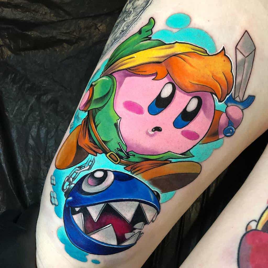 Vibrant tattoo of Kirby as Link from The Legend of Zelda, wielding a sword and wearing a green tunic, with a Chain Chomp beside him