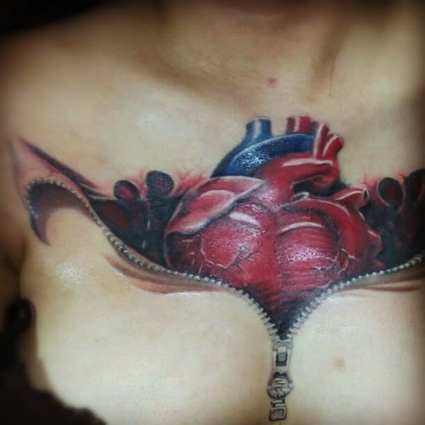Tattoo of a realistic human heart revealed by an unzipped chest design