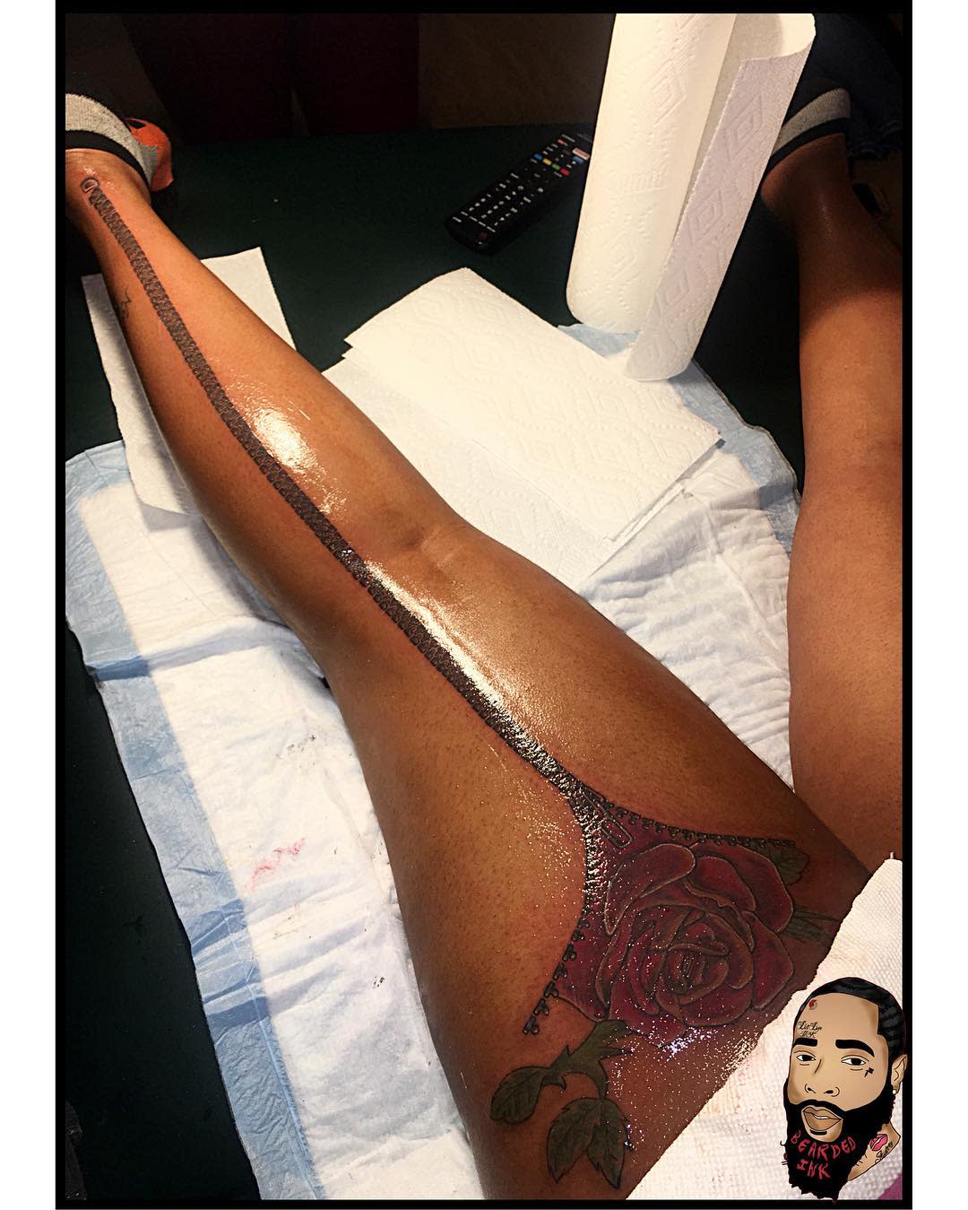 Leg with an intricate red rose tattoo extending up the thigh