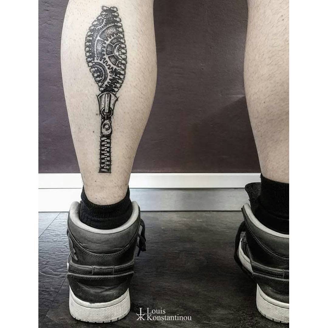 Tattoo of a zipper with visible gears on the back of a calf