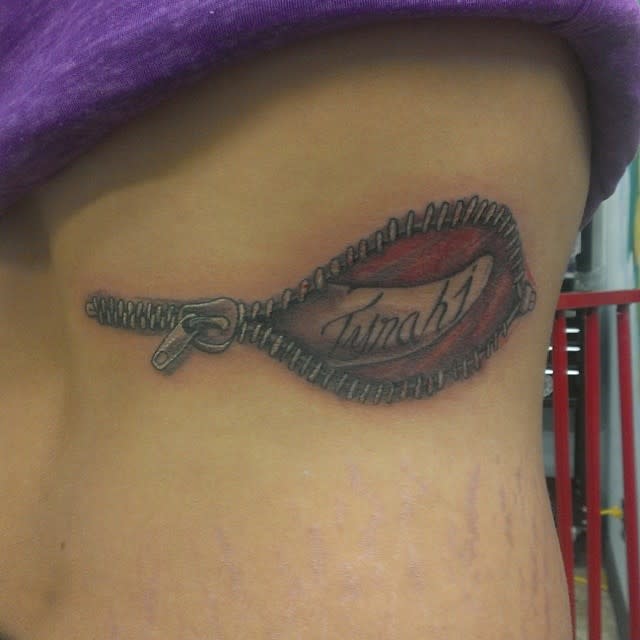 A tattoo of an unzipped zipper revealing the text