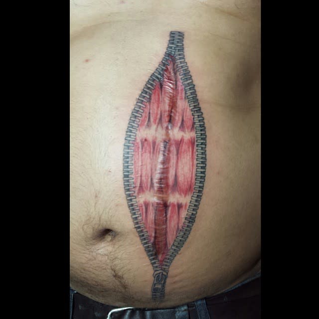 Tattoo of an unzipped zipper revealing muscle tissue on a torso