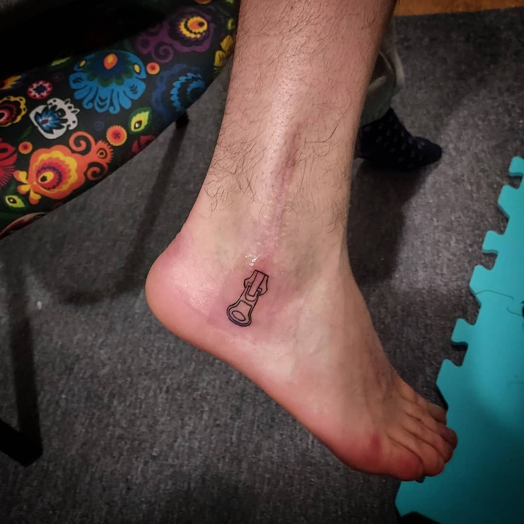 Tattoo of a minimalist zipper on an ankle