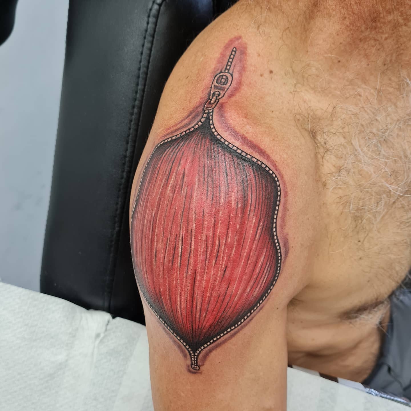 Tattoo of realism-style anatomical muscle on an upper arm