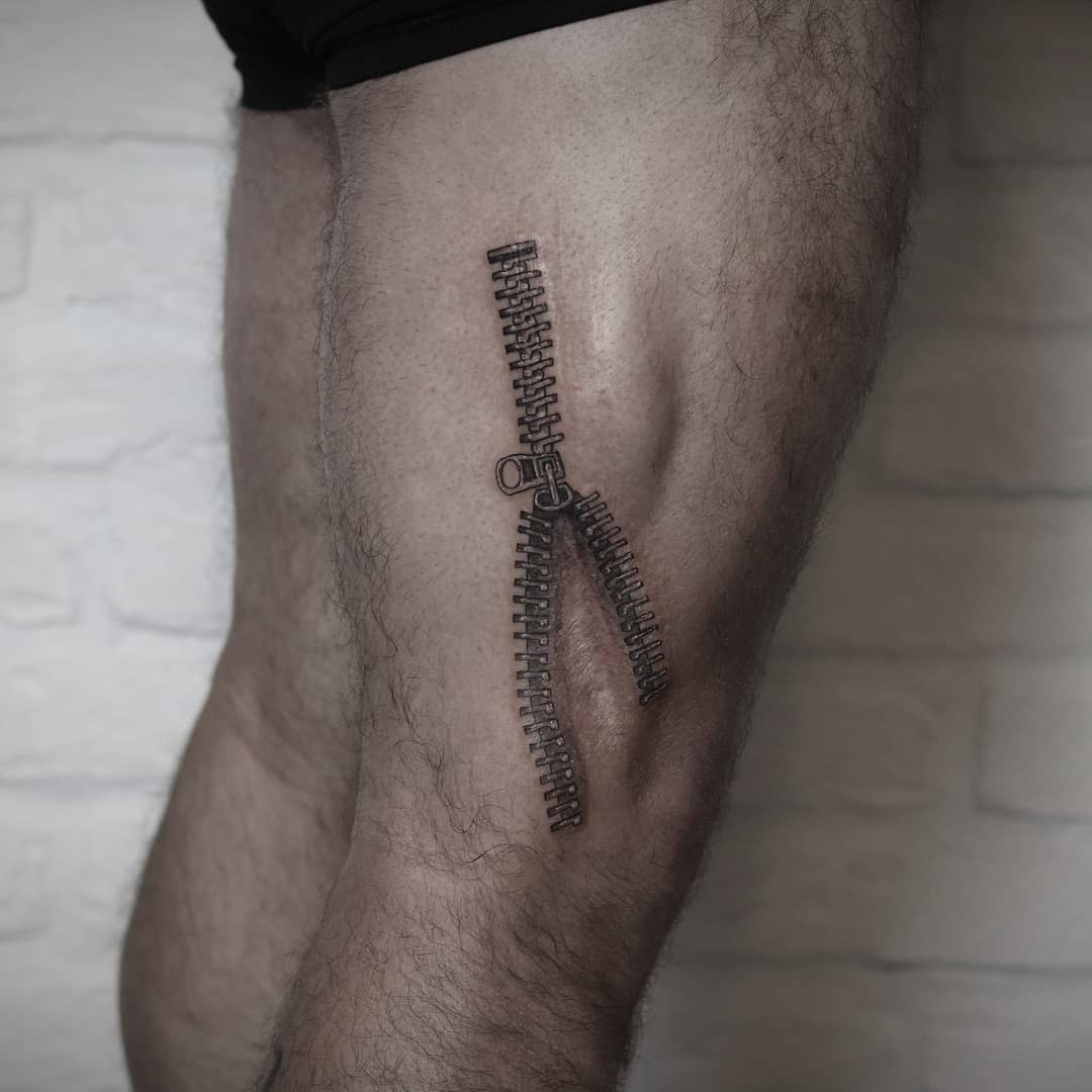 A realistic zipper tattoo on a thigh covering a scar