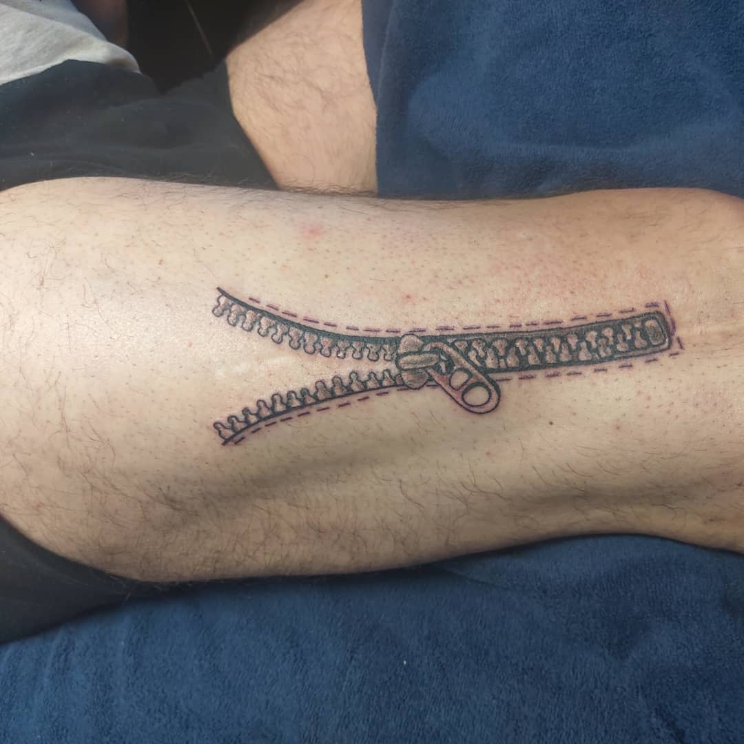 Tattoo of an unzipped zipper on the inner forearm
