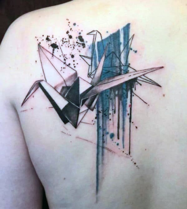 Back tattoo featuring abstract origami cranes with blue and black watercolor splashes