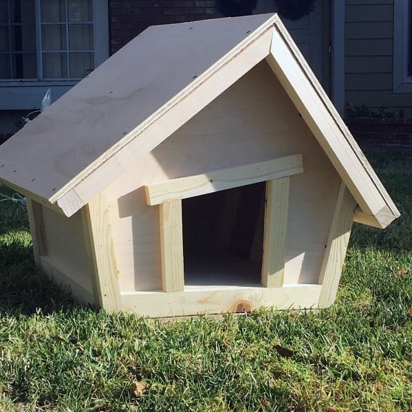 Wooden doghouse with triangular roof on grass