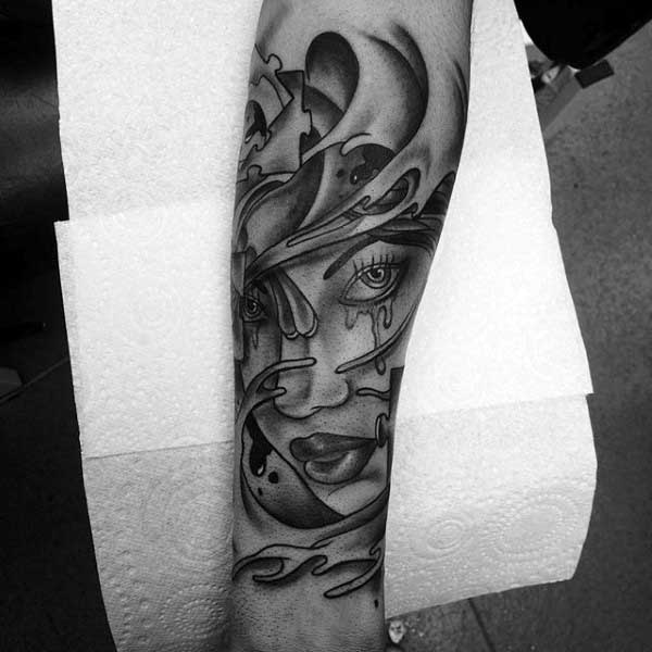Abstract Female Potrait Puzzle Pieces Tattoo On Mans Forearm