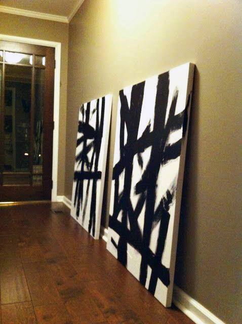 Abstract black and white brushstroke canvas art leaning against a wall on wooden flooring.