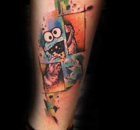 Artistic Cookie Monster tattoo with colorful geometric blocks and splashes, featuring his playful expression and cookie craving.