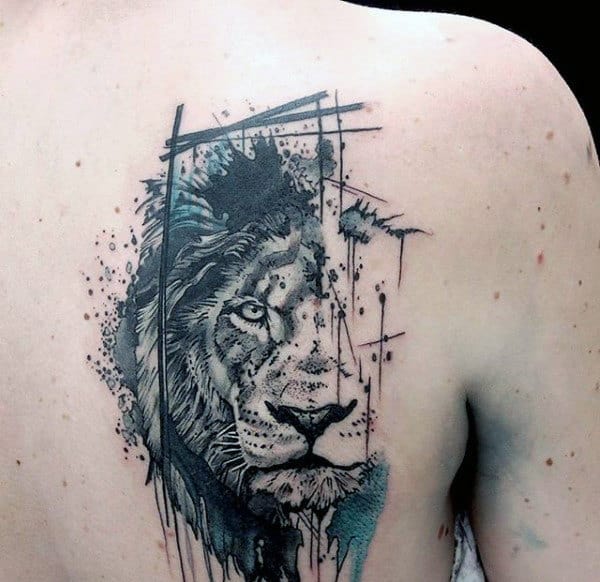 Abstract lion tattoo on a person's shoulder uses ink splatters and geometric shapes