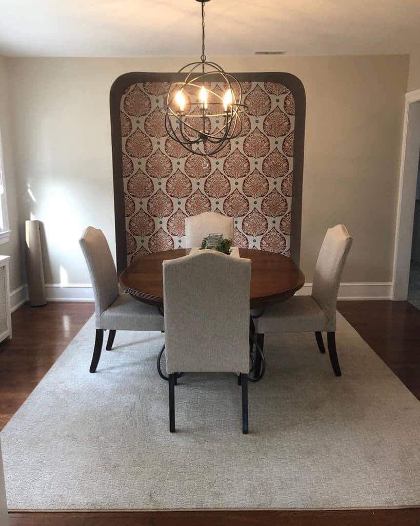 wallpaper accent wall round wood dining table gray chairs chandelier