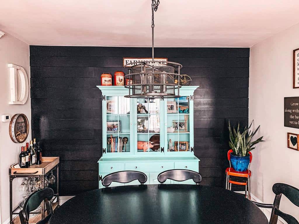 black wood panel accent wall green cabinet black dining table and chairs chandelier