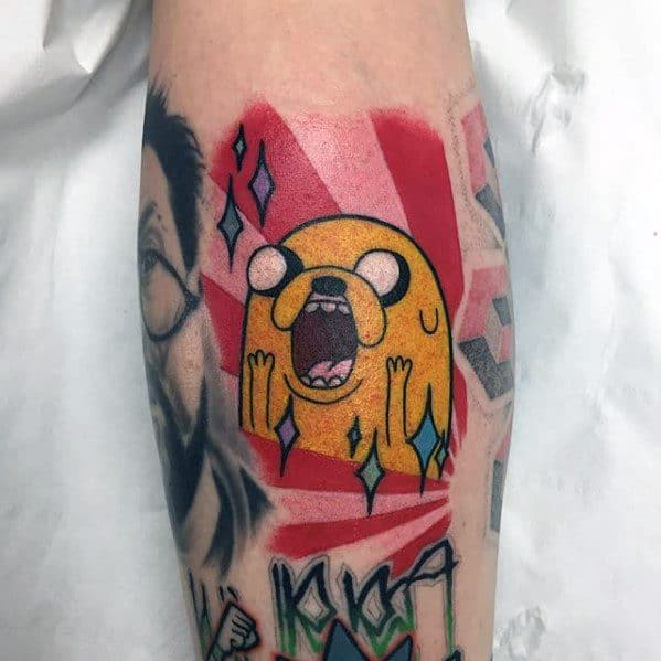 Adventure Time tattoo of Jake the Dog screaming with sparkles and a bold red background, inked on the lower leg.