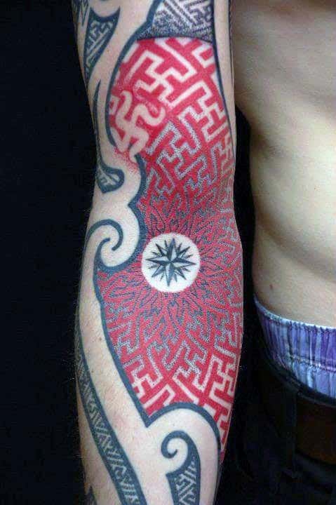 Red and black maze tattoo with a starburst design on a person's forearm