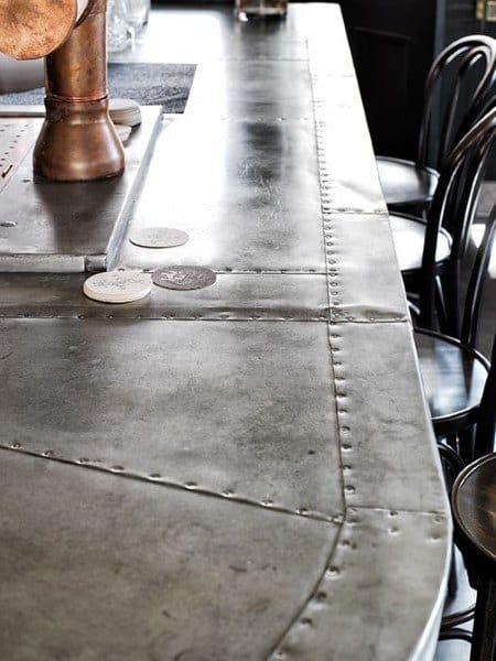Aircraft wing-inspired aluminum bar top with rivet details and industrial-style seating.