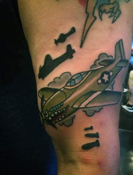 Tattoo of a flying military airplane with bombs and clouds on a person's arm