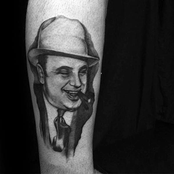 Al Capone tattoo featuring a black-and-white portrait of the infamous gangster, complete with his signature fedora and cigar.