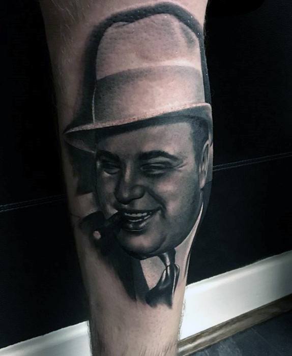 Al Capone tattoo with a detailed black-and-white portrait of the infamous gangster, featuring his iconic fedora and cigar.
