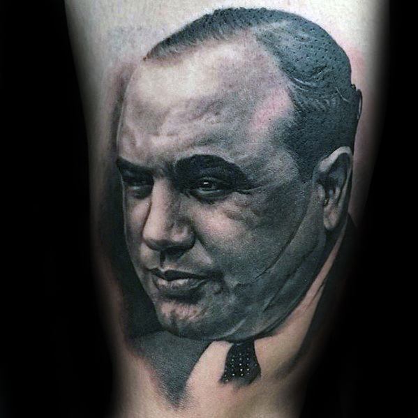 Al Capone tattoo featuring a detailed black-and-white portrait of the notorious gangster with a serious expression.
