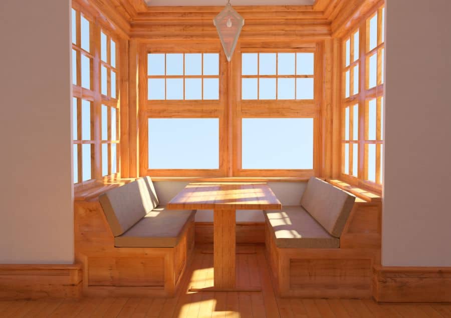 Cozy alcove banquette with wooden table, built-in seating, and neutral window shades.