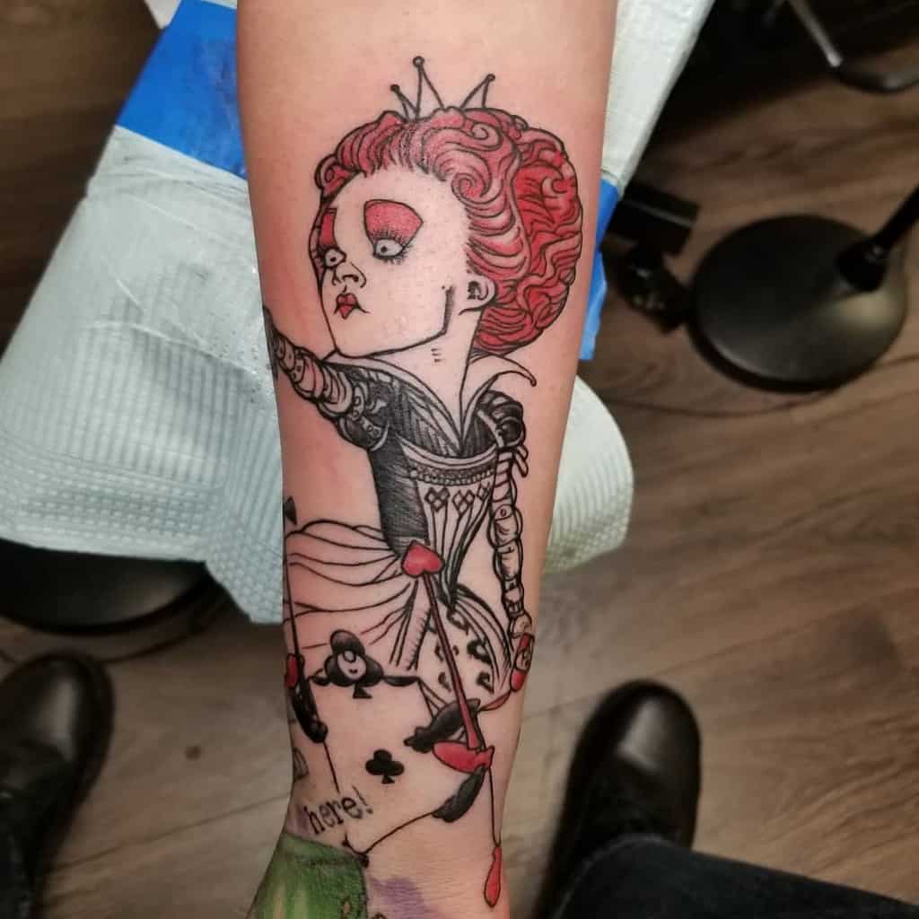 Minimalist Queen of Hearts tattoo in red and black, showcasing her iconic stance and playing card details