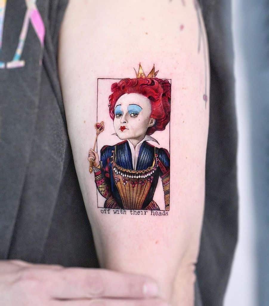 Intricate Queen of Hearts tattoo with vibrant red hair, a golden crown, and the phrase 'Off with their heads' below