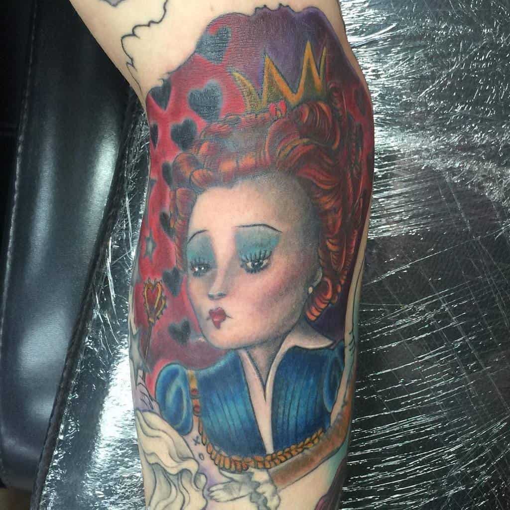 Vibrant Queen of Hearts tattoo featuring a red background, detailed crown, and expressive face with bold blue and red tones