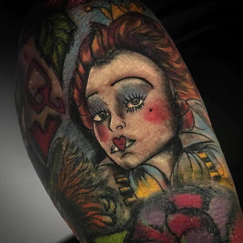 Artistic Queen of Hearts tattoo showcasing bold colors, a heart-shaped lip detail, and intricate surrounding floral accents