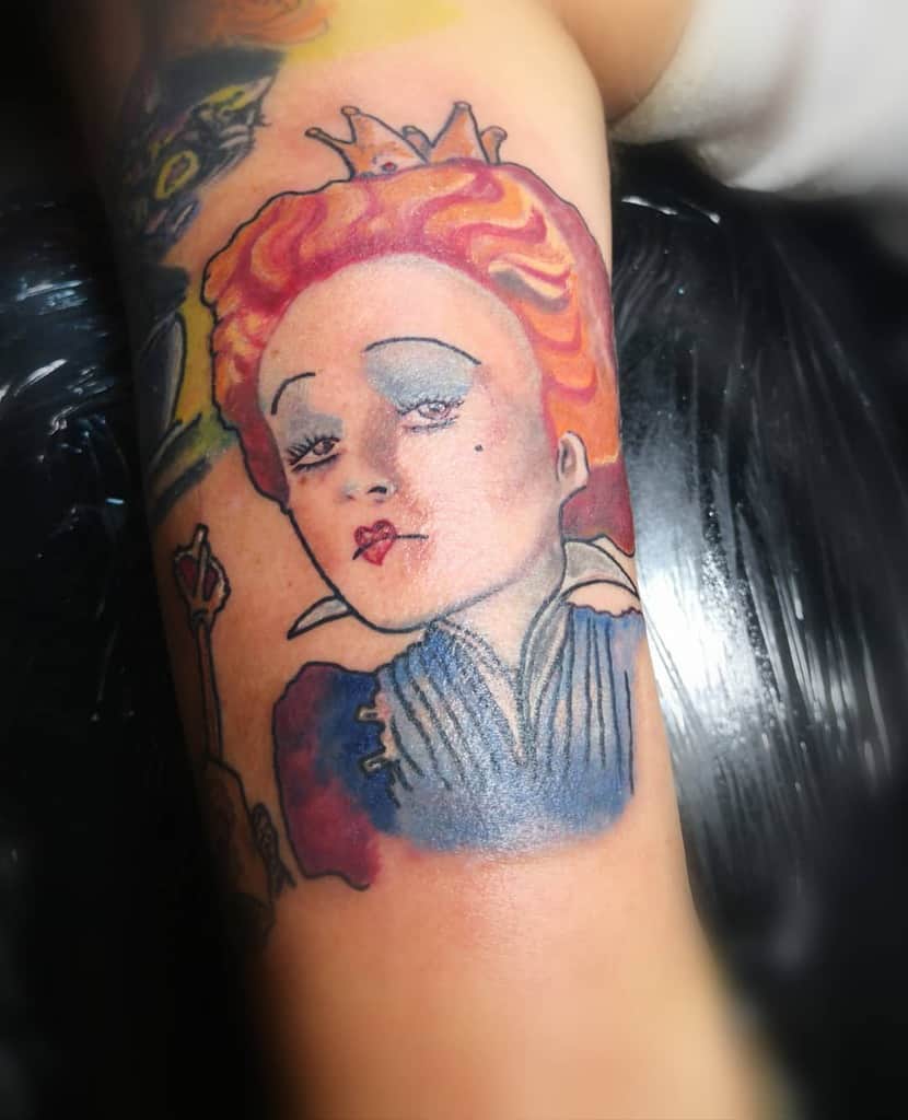 Queen of Hearts tattoo featuring vibrant red hair, a delicate crown, and subtle heart-shaped details for a whimsical touch