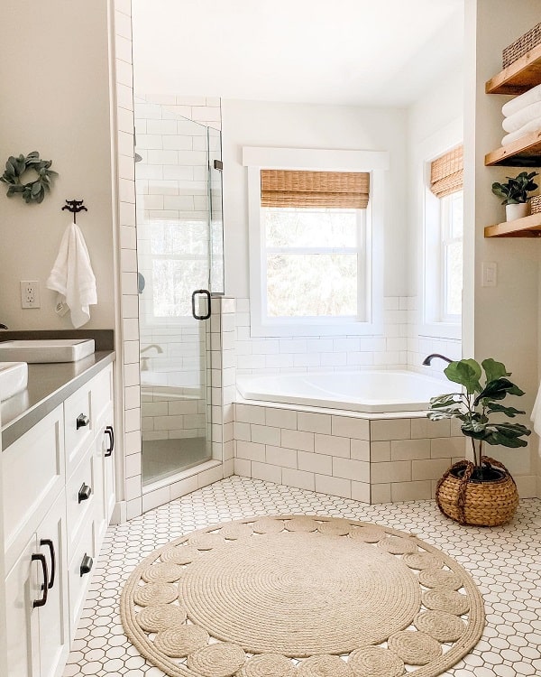 Farmhouse-style bathroom with a glass shower, white tub, hex tile floor, plants, and wooden shelves