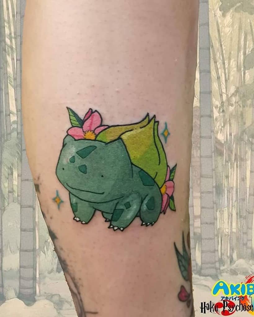 Adorable Bulbasaur tattoo with soft pastel colors, floral accents, and sparkles, giving it a whimsical and nature-inspired touch