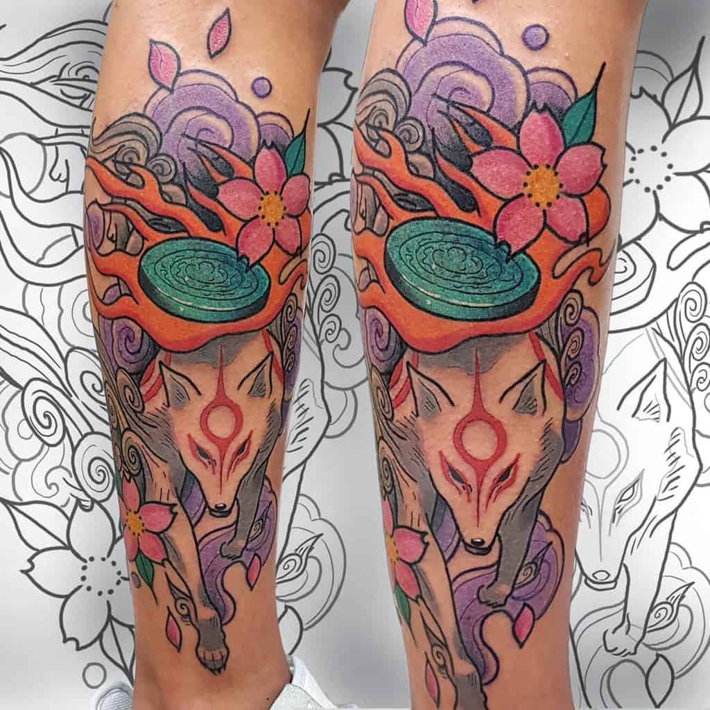 Colorful Okami tattoo of Amaterasu with vibrant cherry blossoms, swirling clouds, and fiery divine energy, blending bold and soft shading