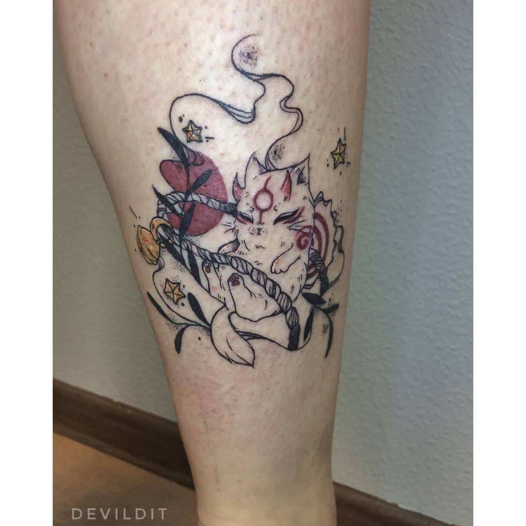 Delicate Okami tattoo of a chibi-style Amaterasu resting on a flower, surrounded by celestial elements and soft red accents