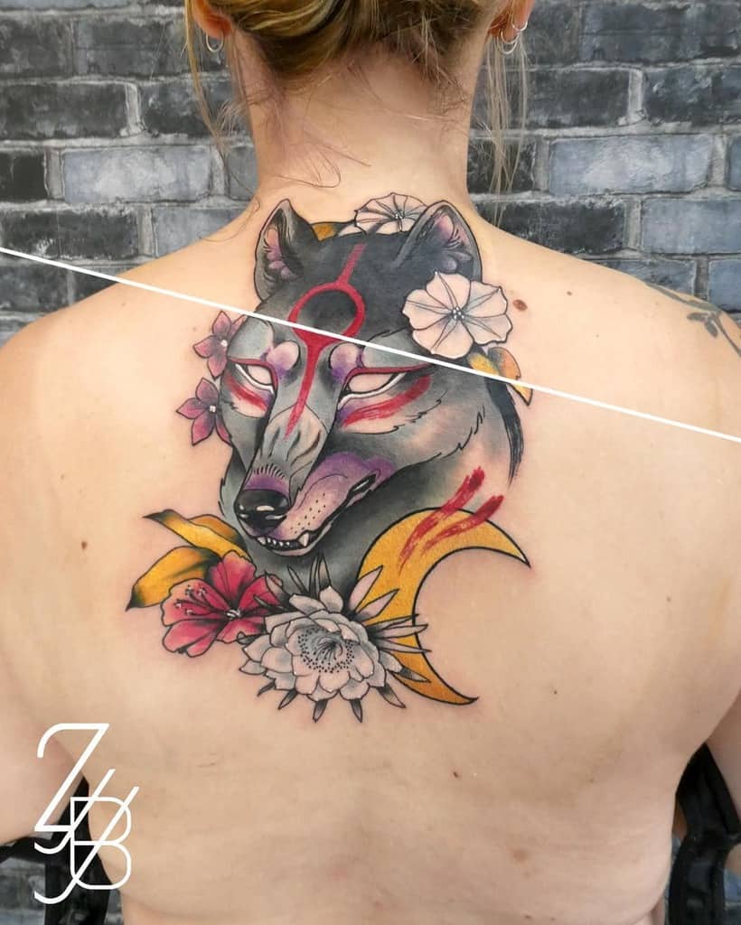 A back tattoo of an Okami wolf surrounded by flowers, blending bold black lines with soft red and pink hues