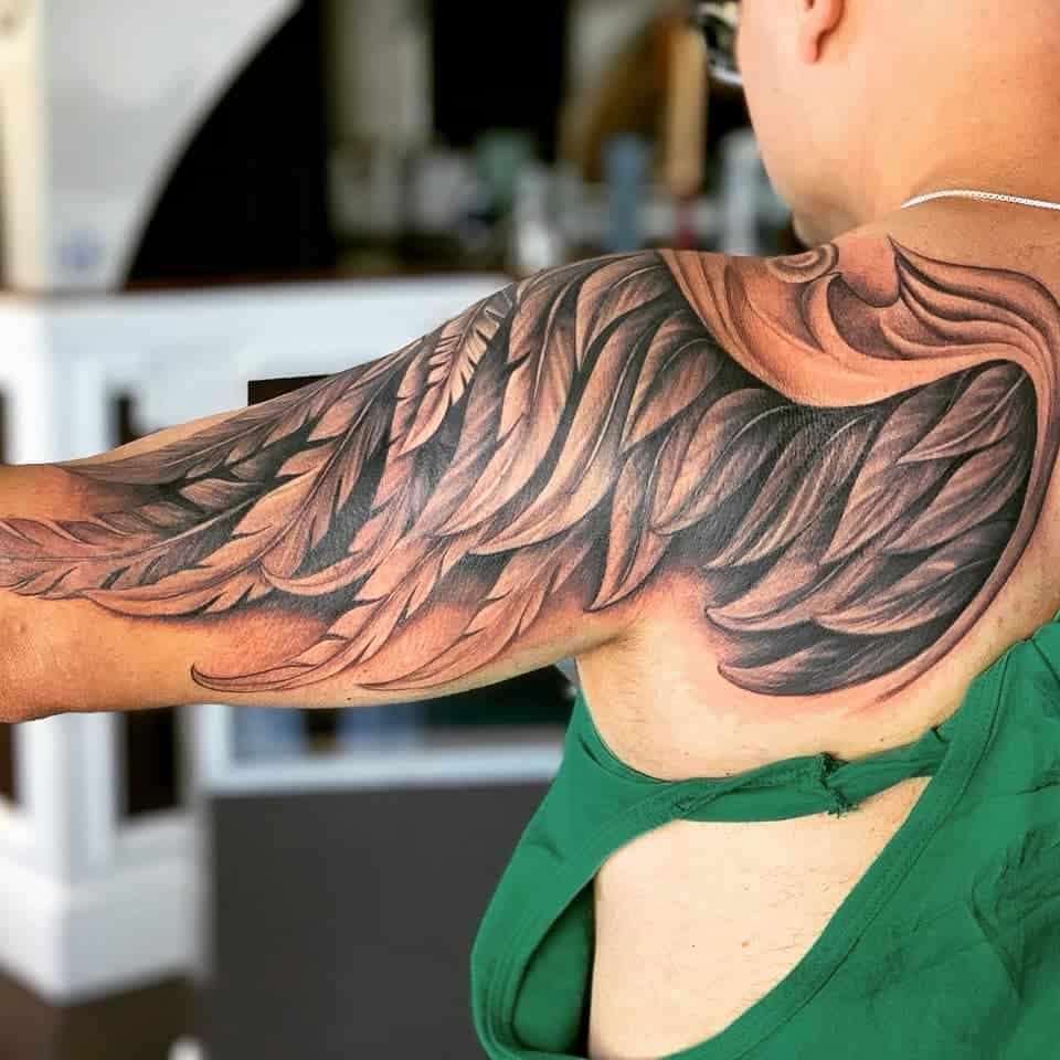 Full arm tattoo of detailed single angel wing, showcasing intricate shading and a dynamic, flowing design
