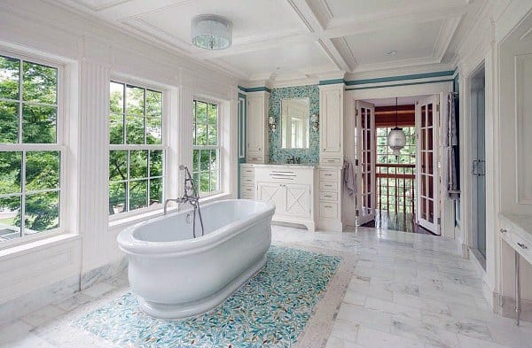 Bright bathroom with freestanding tub, large windows, mosaic floor, and coffered ceiling.