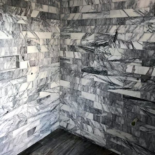 Room with gray and white marble tiles, featuring a sleek shower and dark marble floor