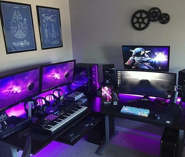 A gaming and music production setup with multiple monitors, a keyboard, purple lighting, and sci-fi decor