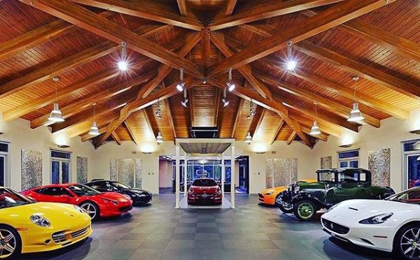 A stylish garage with wood-beam ceilings, luxury cars, and a hidden floor lift.