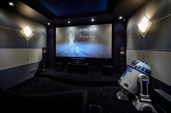 Home theater room with a large screen, concert imagery, speakers, and an R2-D2 replica