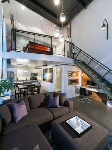 Modern loft interior with open layout, dark sofa, metal staircase, and stylish lighting.