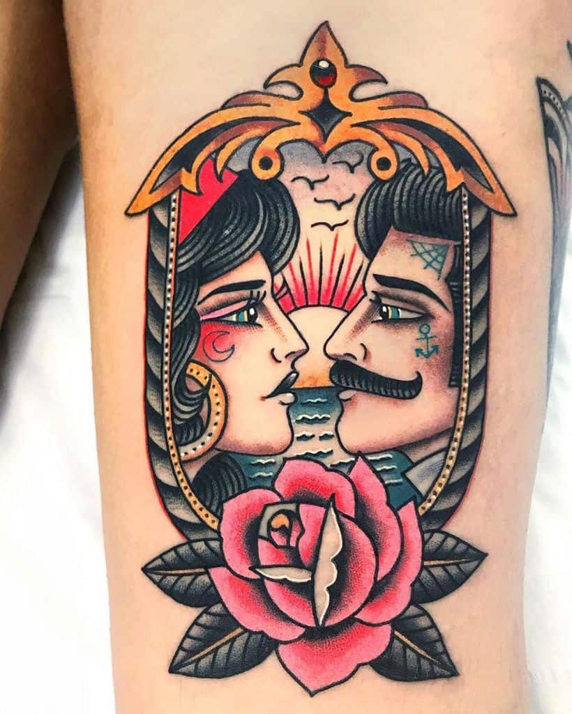Traditional tattoo of a gypsy woman and a sailor gazing at each other in an ornate frame, with a red rose and ocean sunset background.