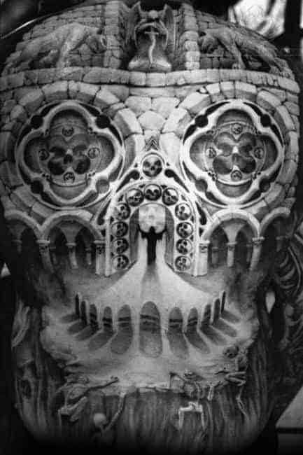 Back tattoo depicting a detailed skull and gothic architecture