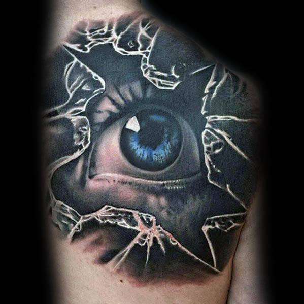 Hyper-realistic tattoo of a vivid blue eye staring through shattered glass, with sharp cracks and intense shadow detailing.
