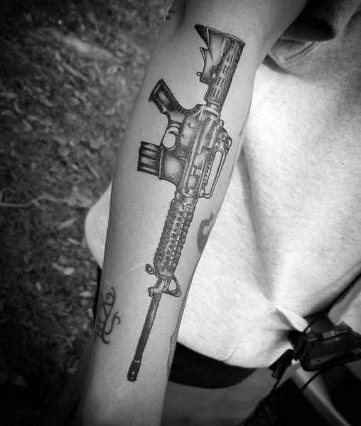 Realistic black and grey AR-15 tattoo on the forearm, featuring intricate shading and fine details, symbolizing strength, precision, and tactical readiness.