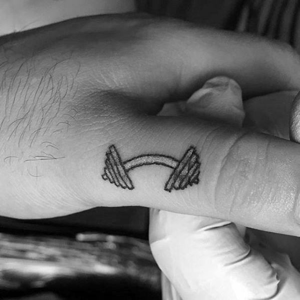Minimalist barbell tattoo on finger symbolizing strength and fitness, with clean black linework and compact design.